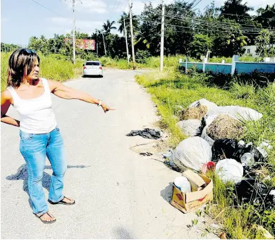  ?? CONTRIBUTE­D PHOTOS ?? Sandra Estrada, vice-president of the Bogue Heights Citizens’ Associatio­n, points out illicitly disposed waste material along the roadway adjoining the St James-based community, an issue which has reportedly been ongoing for several years.