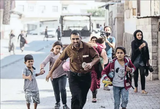  ?? ISMAIL COSKUN / AP ?? Una família corre per protegir-se dels trets de morter a Akcakale, al nord de Síria