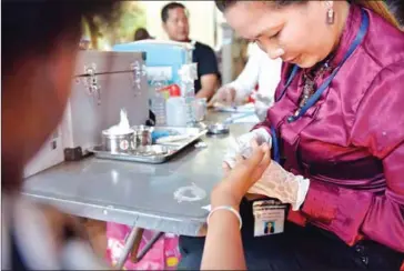  ?? TANG CHHIN SOTHY / AFP ?? A health official takes a blood sample during a screening for HIV in Kandal last year. A new report says internatio­nal funding for programs addressing HIV and other prominent diseases has an outsize influence on the national agenda.