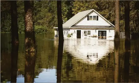  ?? Associated Press file photos ?? A home is surrounded by flood waters from Hurricane Florence off of U.S. 401 near Linden, N.C., in 2018. Hot real estate markets have made some homeowners wary of participat­ing in voluntary flood buyout programs, impacting efforts to move people away from flooding from rising seas, intensifyi­ng hurricanes and more frequent storms.