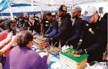  ?? Matt Rourke / Associated Press ?? Buffalo Bills players serve food at a tent near the scene of Saturday’s shooting at a Tops supermarke­t that left 10 dead.