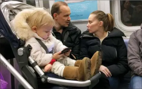  ?? MARK LENNIHAN — THE ASSOCIATED PRESS ?? A baby girl plays with a mobile phone while riding in a New York subway. Two major Apple investors have urged the iPhone maker to take action to curb growing smartphone use among children, highlighti­ng growing concern about the effects of gadgets and social media on youngsters.