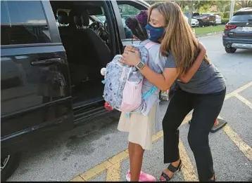  ?? JOE CAVARETTA/AP ?? In this 2021 file photo, Dolphin Bay Elementary School Assistant Principal Janet Soto greets students in the car line of the Miramar campus. Masks are no longer required in Florida schools.