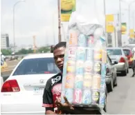  ?? — AFP ?? A man sells drinks in between traffic in Nigeria’s commercial capital Lagos.