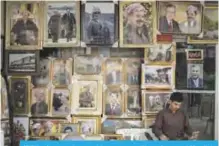  ?? — AP ?? IRBIL: A man sits outside a store selling photos of Kurdish President Masoud Barzani and members of his family.