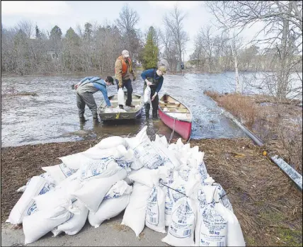  ?? CP PHOTO ?? Residents transport sandbags to their homes cut off by flood waters in Rothesay, N.B. Swollen rivers across New Brunswick are still rising, flooding streets and properties and forcing people from their homes in several communitie­s.