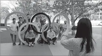  ?? GREGORIO BORGIA/AP PHOTO ?? A group of students from Uruguay pose for a souvenir picture on the Olympic Rings set outside the Olympic Stadium in Tokyo on Saturday. The opening of the the Tokyo Games in four months is in doubt with more voices suggesting the games should to be postponed because of the worldwide pandemic.