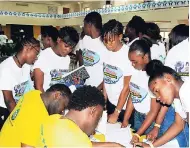  ??  ?? Students line up to ‘pay’ utility bills at the Credit Union Reality Fair. Two volunteers assist the students.