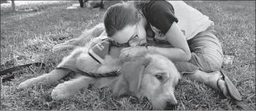  ?? MATT MCCLAIN/WASHINGTON POST ?? Alexandra Geisser, 16, embraces a therapy dog named Mickey outside Marjory Stoneman Douglas High School.