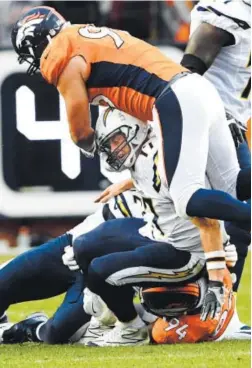  ??  ?? DeMarcus Ware, bottom, gets some help from Jared Crick in bringing San Diego QB Philip Rivers to the ground in October. Joe Amon, The Denver Post