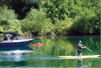  ?? COURTESY PHOTOGRAPH/RICH HANNER ?? The rover, tethered to a Jetcraft vessel, scans the Mokelumne River during a test run as a paddle boarder cruises nearby.