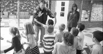  ?? MICHAEL CONROY/THE ASSOCIATED PRESS ?? Forest Dale Elementary School Principal Deanna Pitman and Carmel police officer Greg DeWald welcome students as they return to the school after an intruder drill at the school in Carmel, Ind., earlier this month.