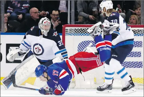  ?? THE ASSOCIATED PRESS ?? Rangers winger Jesper Fast goes for a tumble in front of Jets goalie Steve Mason and defenceman Joe Morrow during the opening period in New York on Tuesday night. Mason, who picked up his first shutout of the season, was making his first start since...