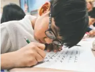  ?? THE ASSOCIATED PRESS ?? A third-grader practices his cursive handwritin­g earlier this month at P.S. 166 in the Queens borough of New York.