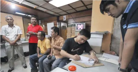  ?? REYNAN VILLENA ?? Incumbent Adlaon, Cebu City Barangay Captain Elvis Narra (seated, writing) files his certificat­e of candidacy along with the candidates under his slate. Narra was the earliest candidate from the north district, arriving at the Comelec office at 8:10...