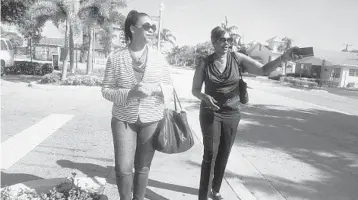  ?? CARLINE JEAN/SOUTH FLORIDA SUN SENTINEL ?? Calisha Anderson, left, and Joycelyn Patrick walk along Northwest Fifth Avenue in Delray Beach. Patrick has been encouragin­g her friends and family to get a vaccine.