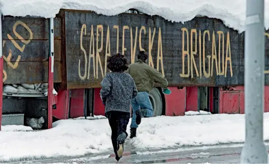  ??  ?? Sarajevo, 1993: A couple runs to shelter from snipers behind a bus carrying the legend “Sarajevo brigade”