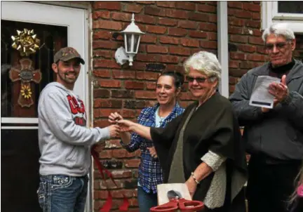  ?? KRISTI GARABRANDT — THE NEWS-HERALD ?? William Meyer and Mary Huge present the keys of the completed house to Bryan and Heather at the Oct. 29 dedication.