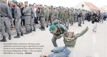  ?? — Reuters ?? An Israeli border policeman removes a prosettlem­ent activist during an operation by Israeli forces to evict residents from several homes in the Israeli settlement of Ofra, in the occupied West Bank, on Tuesday.