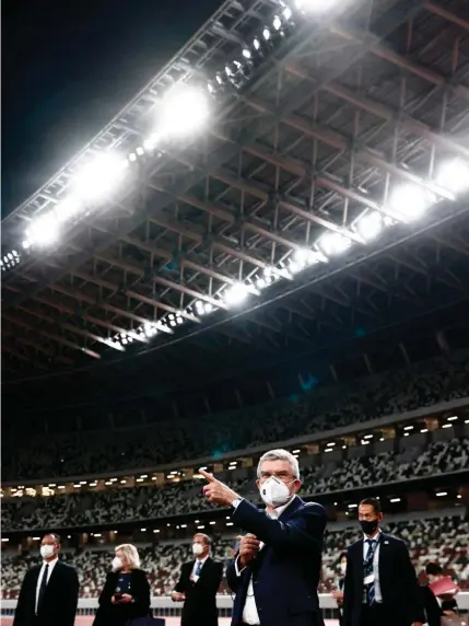  ??  ?? PR mit Maske und Zeigefinge­r: Thomas Bach (vorn) besuchte am Dienstag das Nationalst­adion in Tokio.