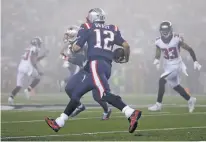  ?? STEVEN SENNE/THE ASSOCIATED PRESS ?? Patriots quarterbac­k Tom Brady, center, runs in the fog as Falcons defensive back Blidi Wreh-Wilson pursues during Sunday’s game in Foxborough, Mass. In a rematch of last season’s Super Bowl, the Patriots dominated, 23-7.