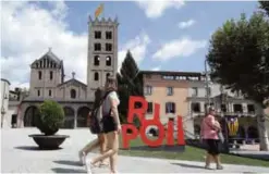  ?? — AFP ?? A picture taken yesterday shows people passing by the Monastery of Santa Maria and a city sign in Ripoll.