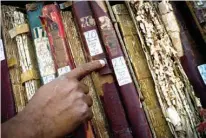  ?? Associated Press ?? A man searches among volumes labeled “Whites” on Jan. 12 as part of an effort to digitize colonial-era registries of blacks and whites at the Espiritu Santo Church in Old Havana, Cuba. “That’s how these books where placed, books for whites, books for...