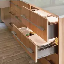  ??  ?? Above In the kitchen, everything is streamline­d to maximize storage and prevent clutter. The custom trough sink is outfitted with several cutting boards, while lower drawers contain dishware, cutlery, and cookware