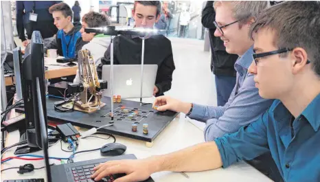  ?? FOTOS: ANDRE WEISSER/PR ?? Landen mit ihrem „SpieleBot“in der Kategorie „Mathematik & Informatik“auf dem ersten Platz: Frank Hengstler, Leon Maurer und Daniel Pasenko von der Claude-Dornier-Schule. Noch spielt der Roboterarm nur Spiele wie Mühle, doch die Schüler träumen davon,...