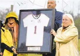  ?? SABRINA SCHAEFFER/AP ?? University of Virginia athletic director Craig Littlepage presents Yeardley Love’s sister Lexie, left, and mother, Sharon, with a jersey with Yeardley’s number.