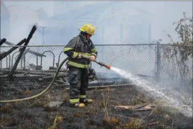  ?? ERIC BONZAR — THE MORNING JOURNAL ?? A firefighte­r dowses hotspots while crews battle a detached garage fire at a home in the 1500 block of Fillmore Avenue on July 6, 2016.