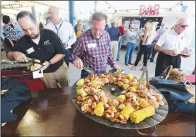  ?? NWA Democrat-Gazette/DAVID GOTTSCHALK ?? Charles Hester (center), with Cram-A-Lot, selects shrimp Thursday at Shiloh Square during the seventh annual Chickin, Peelin’ & Politickin’ event in Springdale. Regional civic and business leaders have the opportunit­y to speak with national, state, regional and local political leaders and elected officials at the event, which is organized by the Springdale Chamber of Commerce.