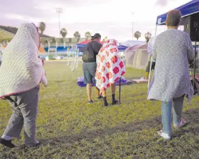  ??  ?? • Varias personas se ponen de pie tras pasar la noche en un estadio de beisbol tras un sismo de magnitud 6.4 en Guayanilla, Puerto Rico.