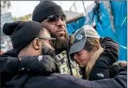  ?? The New York Times/ERIN KIRKLAND ?? General Motors workers embrace Friday outside the Flint Assembly Plant in Flint, Mich., after hearing that members of the United Auto Workers union had voted to approve a new contract with GM.