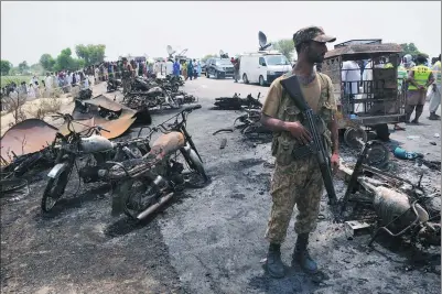  ?? REUTERS ?? A soldier stands guard amid the wreckage of burnt-out cars and motorcycle­s at the scene of an oil tanker explosion in Bahawalpur, Pakistan, on Sunday.