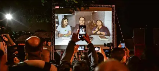  ?? Avener Prado/Folhapress ?? Eleitores assistem ao primeiro pronunciam­ento de Jair Bolsonaro em telão na frente de sua casa