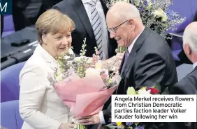  ??  ?? Angela Merkel receives flowers from Christian Democratic parties faction leader Volker Kauder following her win