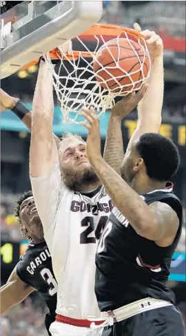  ?? Mark Humphrey Associate Press ?? PRZEMEK KARNOWSKI of Gonzaga dunks over South Carolina’s Sindarius Thornwell during the second half of Saturday’s NCAA tournament semifinal.