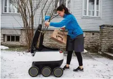  ?? —AFP ?? TALLINN: A woman takes delivery of food from a six-wheeled robot by Starship Technologi­es from restaurant.