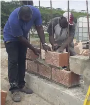  ?? PHOTO BY RASBERT TURNER ?? Councillor Vanrick Preddie (left) helping to build the wall adjoining the Hellshire main road in Portmore, St Catherine.