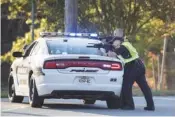  ?? STAFF PHOTO BY TROY STOLT ?? East Ridge Police officers take cover during a standoff near Lake Winnepesau­kah Amusement Park on Oct. 18 in Rossville, Ga. Several officers present during the standoff have since tested positive for COVID-19.