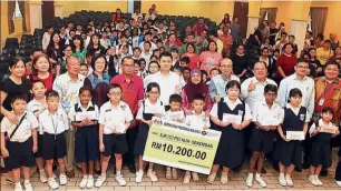  ??  ?? Timely contributi­on: Chong (centre) presenting aid to needy students at SJK(C) Pei Hua in Seremban.