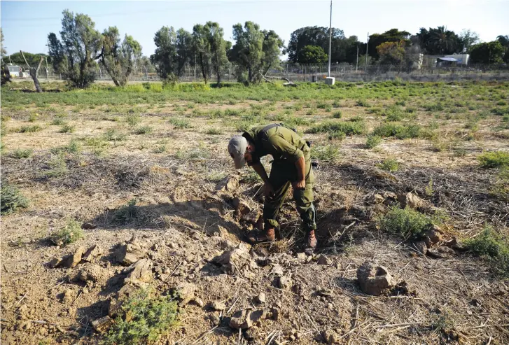  ?? (Reuters) ?? A SOLDIER inspects an impact of a Hamas rocket. The terrorist group has launched hundreds of rockets at Israel in recent weeks.