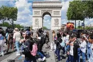  ?? Michel Euler/Associated Press ?? Tourists cross the Champs-Elysees avenue with the Arc de Triomphe in the background in Paris.