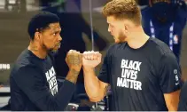  ??  ?? Heat’s Udonis Haslem, left, and Meyers Leonard, right, show solidarity for the Black Lives Matter movement, though Leonard didn’t join in kneeling during the national anthem.