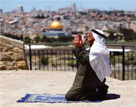  ?? Reuters ?? A Muslim worshipper offers his Friday prayer outside Jerusalem’s Old City amid the coronaviru­s restrictio­ns. Al-Aqsa Mosque in the city is one of Islam’s three holy sites.