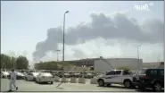  ?? AL-ARABIYA—ASSOCIATED PRESS ?? In this image made from a video broadcast on the Saudiowned Al-Arabiya satellite news channel on Saturday, Sept. 14, 2019, a man walks through a parking lot as the smoke from a fire at the Abqaiq oil processing facility can be seen behind him in Buqyaq, Saudi Arabia. Drones launched by Yemen’s Houthi rebels attacked the world’s largest oil processing facility in Saudi Arabia and another major oilfield Saturday, sparking huge fires at a vulnerable chokepoint for global energy supplies.