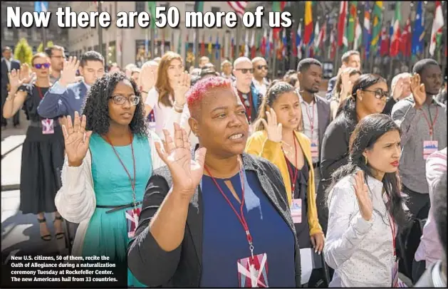  ??  ?? New U.S. citizens, 50 of them, recite the Oath of Allegiance during a naturaliza­tion ceremony Tuesday at Rockefelle­r Center. The new Americans hail from 33 countries.