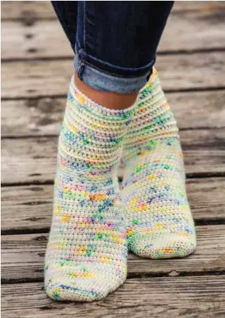  ??  ?? You’ll enjoy crocheting these fun socks with splashes of bright color as much as you will love wearing them! Linked double crochet stitches create a soft, wearable texture while the corded ridge pattern adds a unique design element.