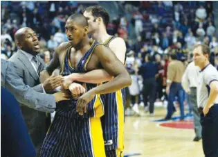  ?? AP PHOTO/DUANE BURLESON ?? Indiana Pacers’ Ron Artest is restrained by Austin Croshere before being escorted off the court following their fight with the Detroit Pistons and fans on Nov. 19, 2004, in Auburn Hills, Mich.